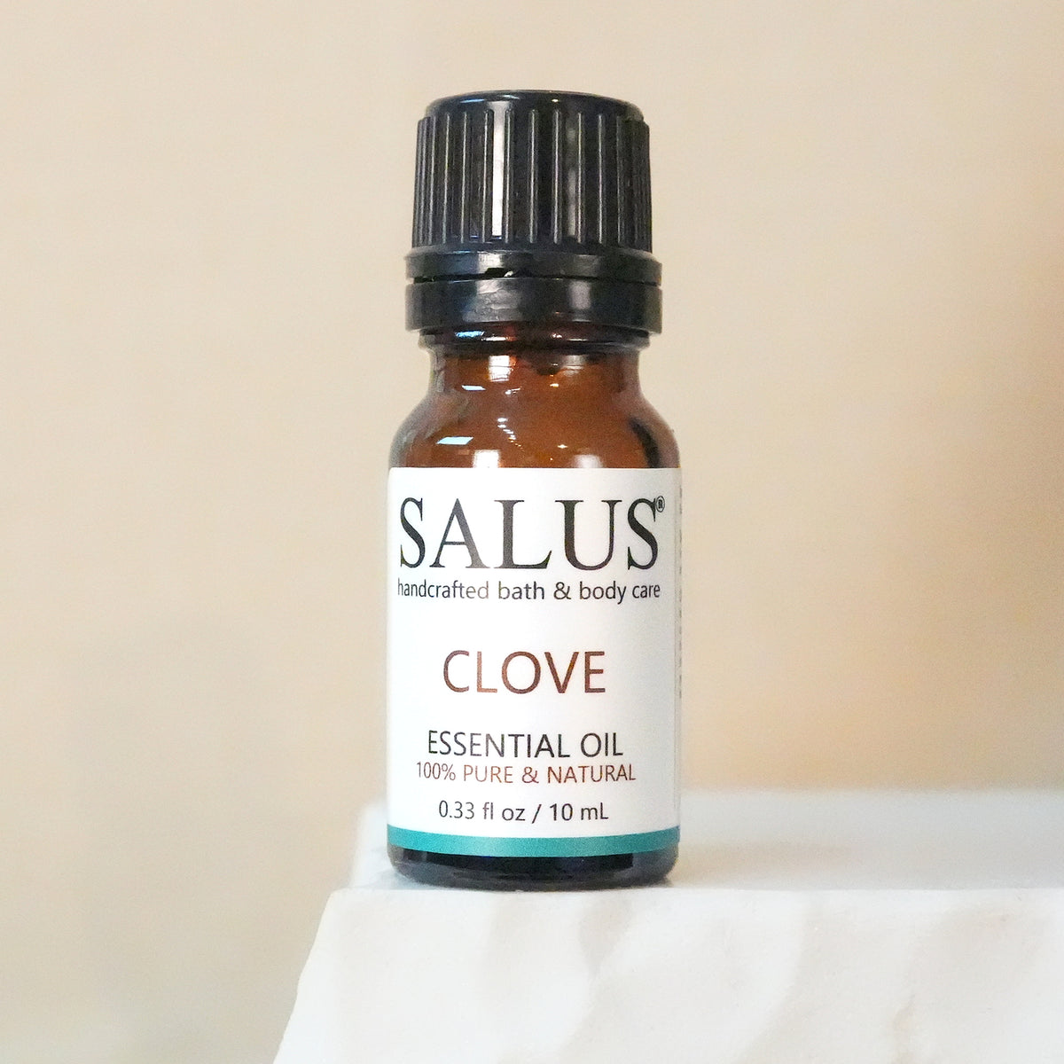 SALUS Clove essential oil, 10 mL amber bottle on a white stone pedestal.
