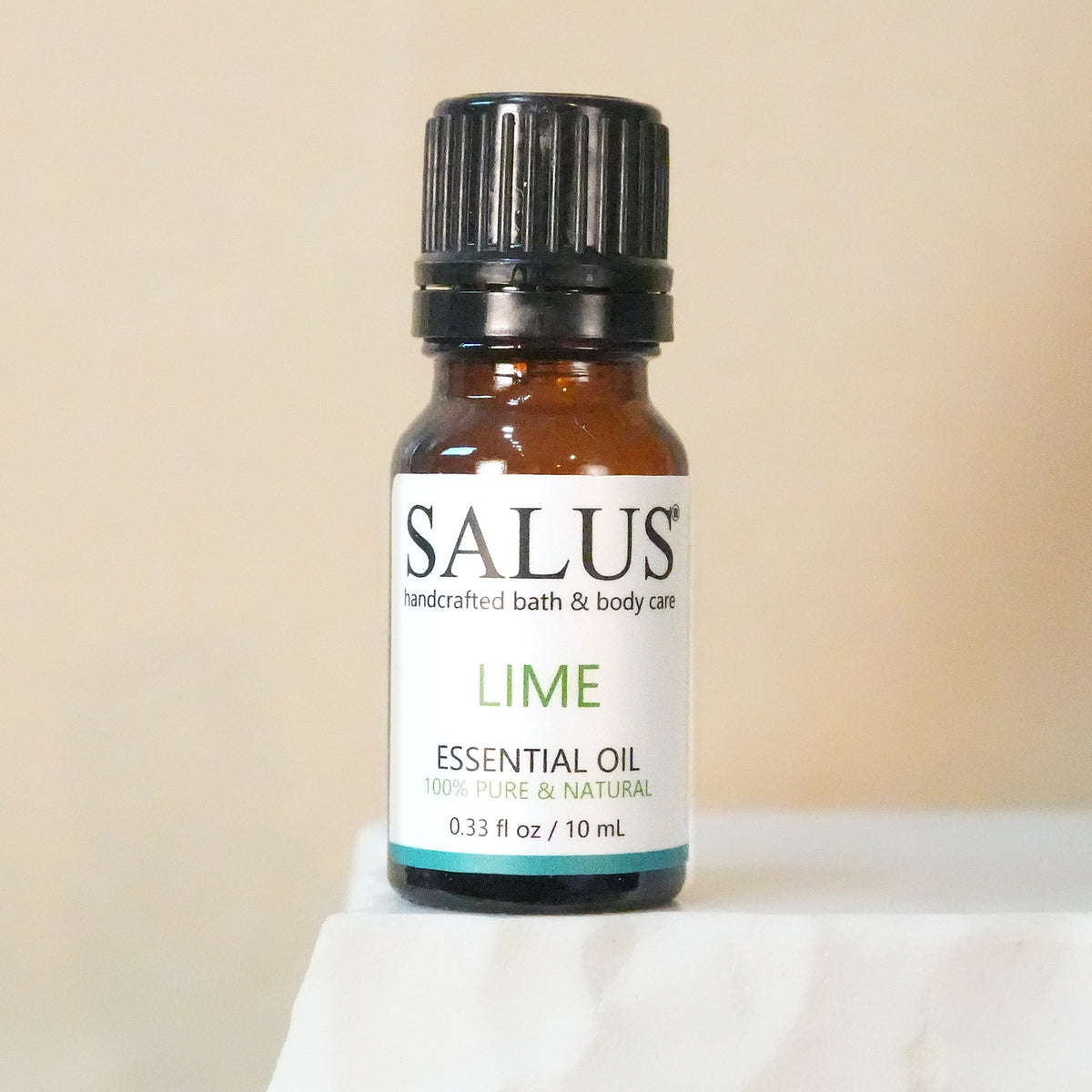 SALUS Lime essential oil, 10 mL amber bottle on a white stone pedestal.