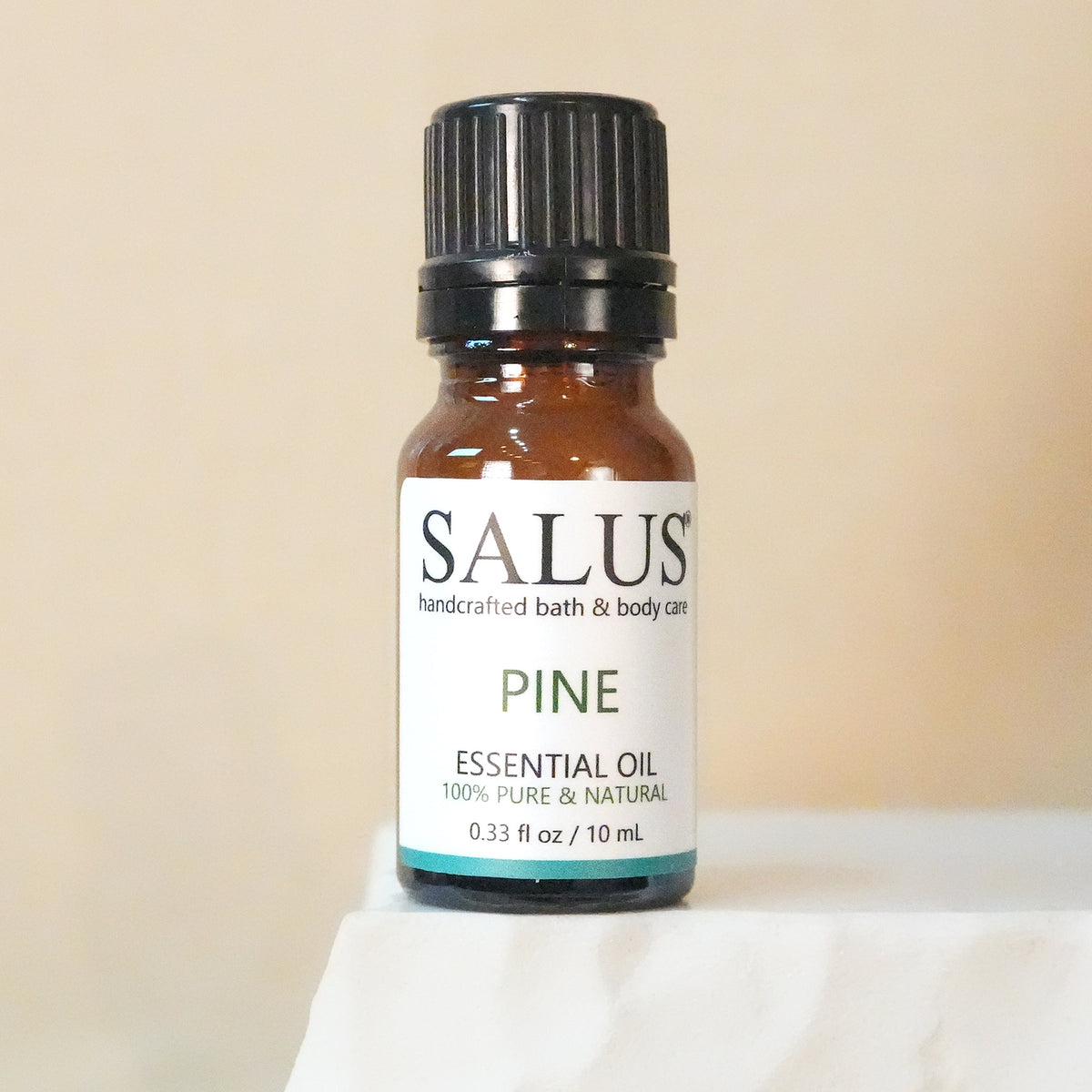 SALUS Pine essential oil, 10 mL amber bottle on a white stone pedestal.