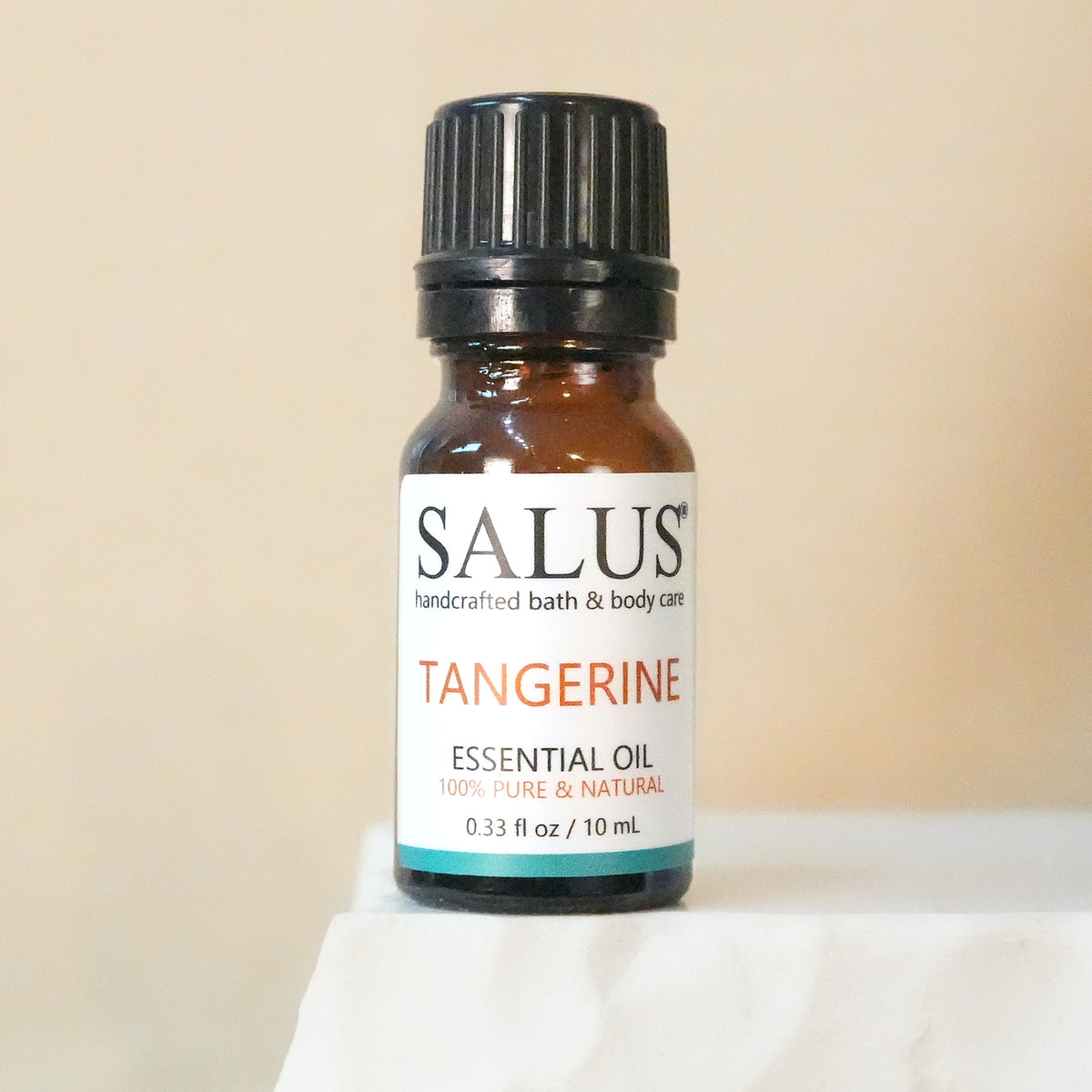 SALUS Tangerine essential oil, 10 mL amber bottle on a white stone pedestal.