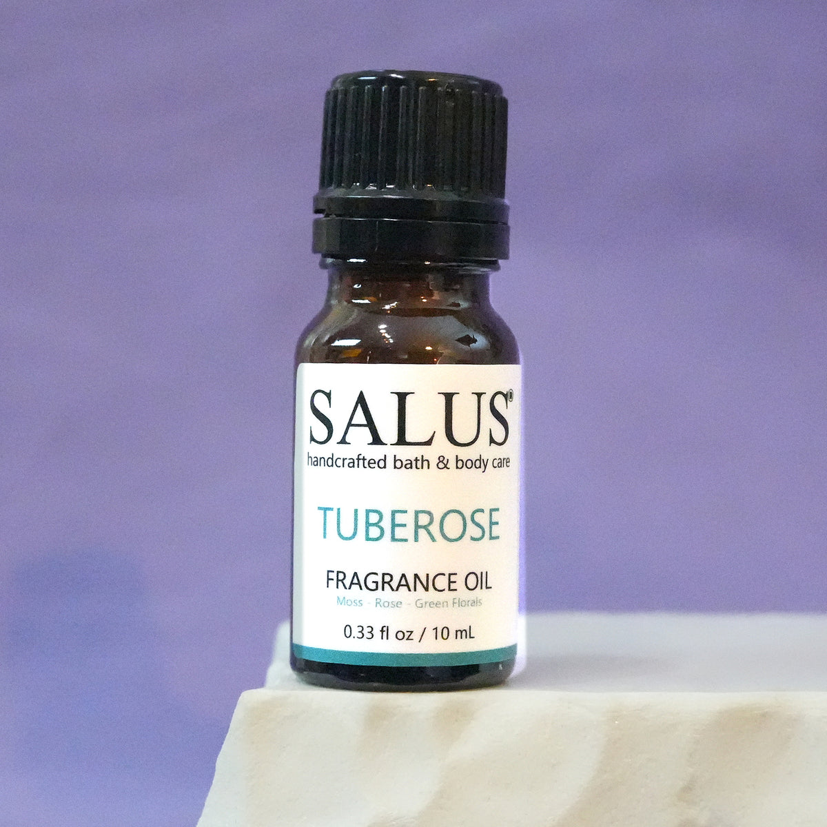 SALUS Tuberose fragrance oil, 10 mL amber bottle on a white stone pedestal.