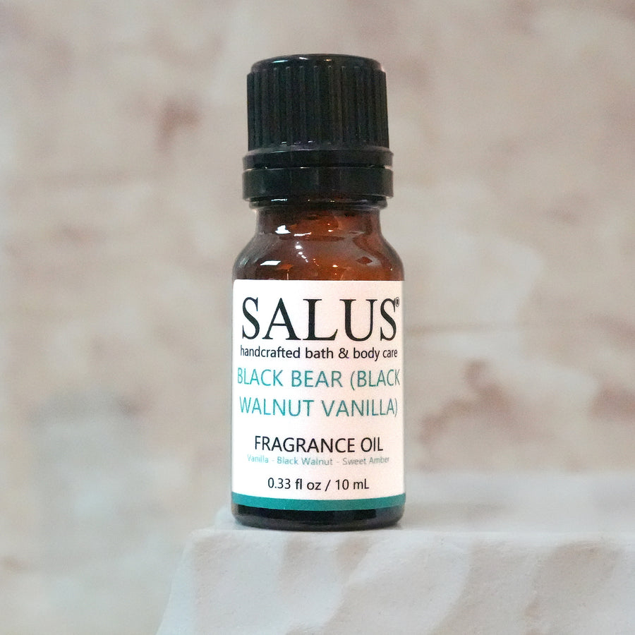 SALUS Black Bear (Black Walnut Vanilla) fragrance oil, 10 mL amber bottle on a white stone pedestal.