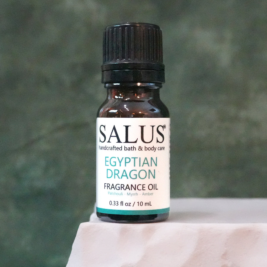 SALUS Egyptian Dragon fragrance oil, 10 mL amber bottle on a white stone pedestal.