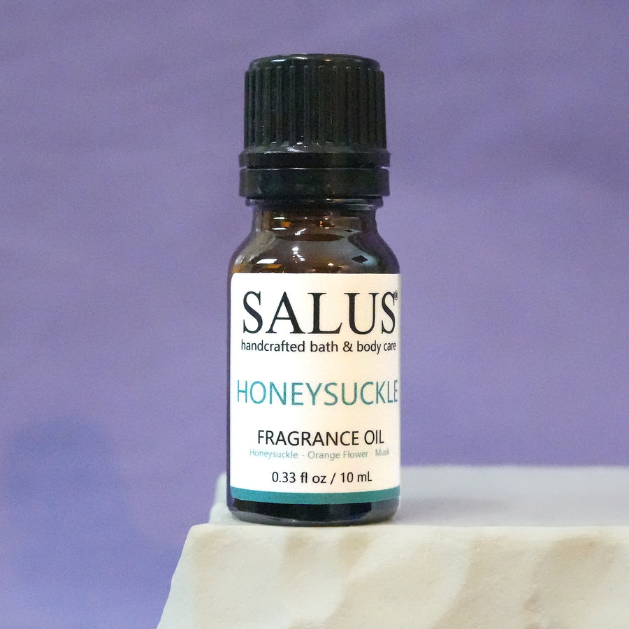 SALUS Honeysuckle fragrance oil, 10 mL amber bottle on a white stone pedestal.