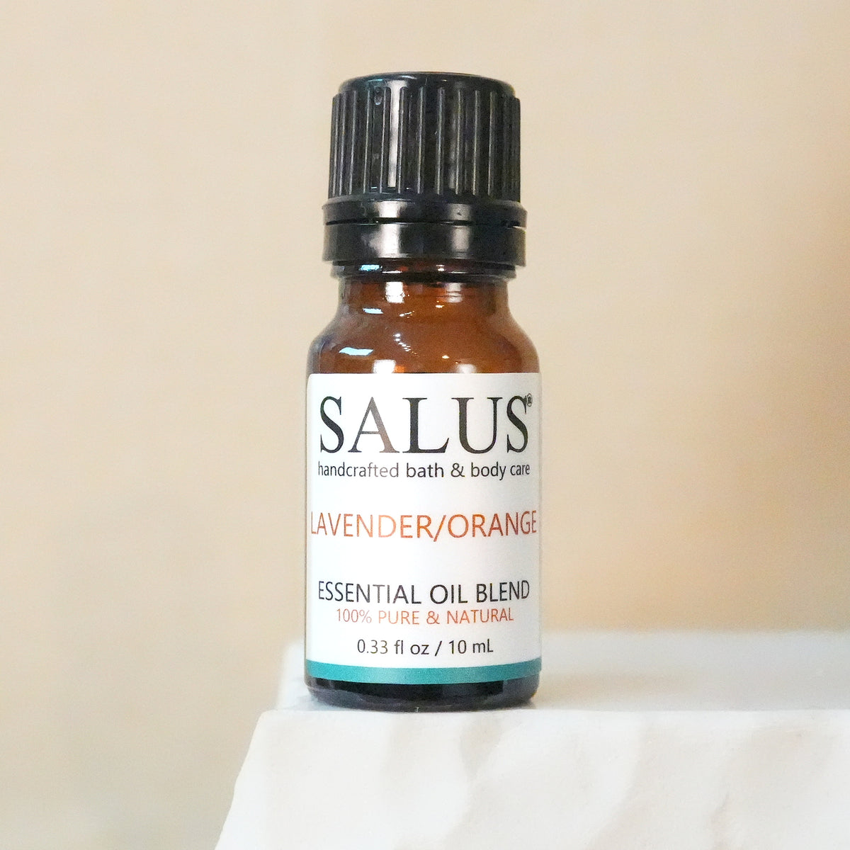 SALUS Lavender/Orange essential oil blend, 10 mL amber bottle on a white stone pedestal.