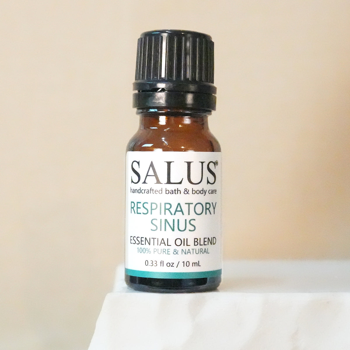 SALUS Respiratory Sinus essential oil blend, 10 mL amber bottle on a white stone pedestal.