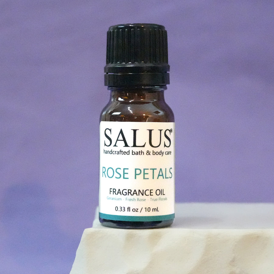 SALUS Rose Petals fragrance oil, 10 mL amber bottle on a white stone pedestal.