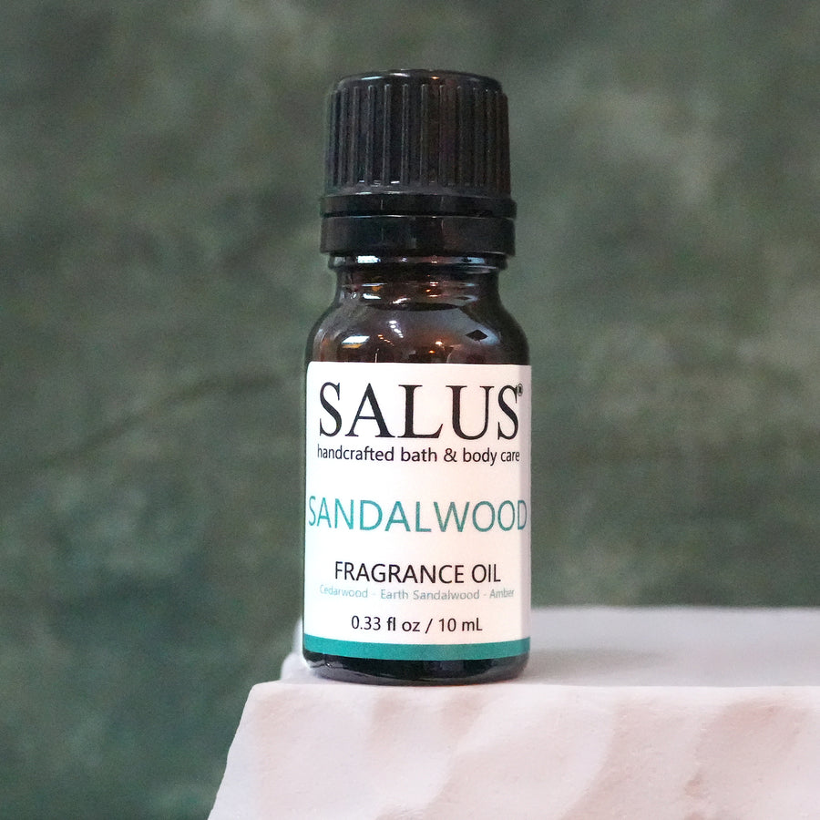 SALUS Sandalwood fragrance oil, 10 mL amber bottle on a white stone pedestal.