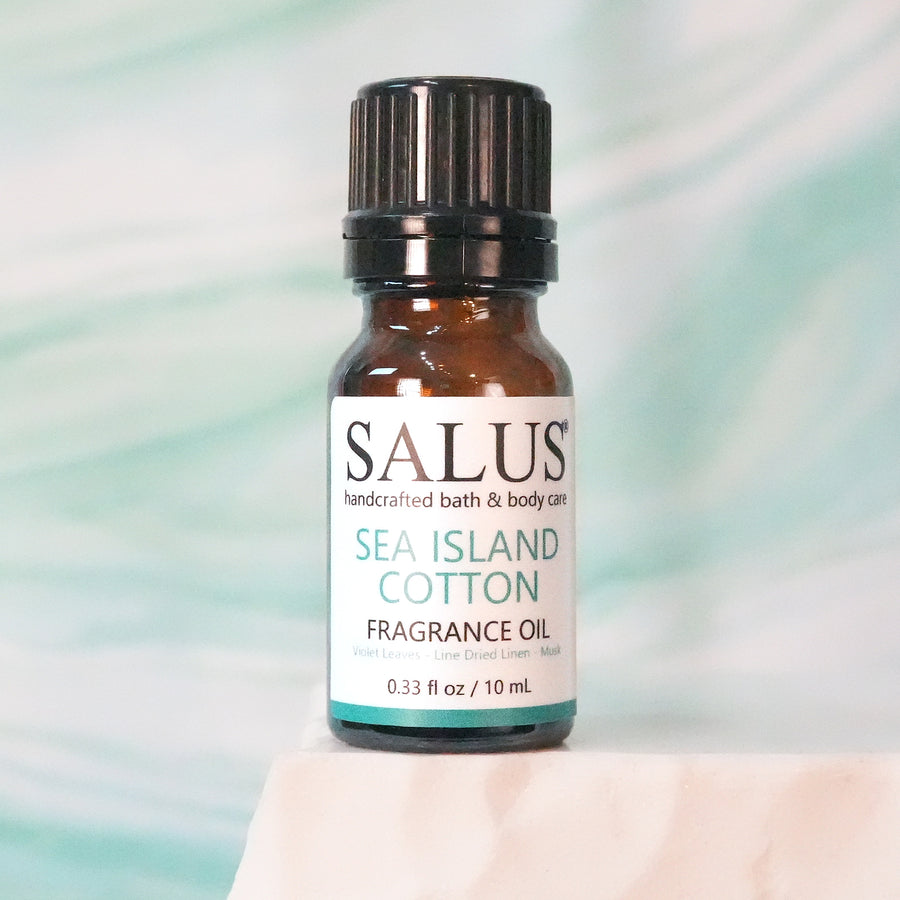 SALUS Sea Island Cotton fragrance oil, 10 mL amber bottle on a white stone pedestal.