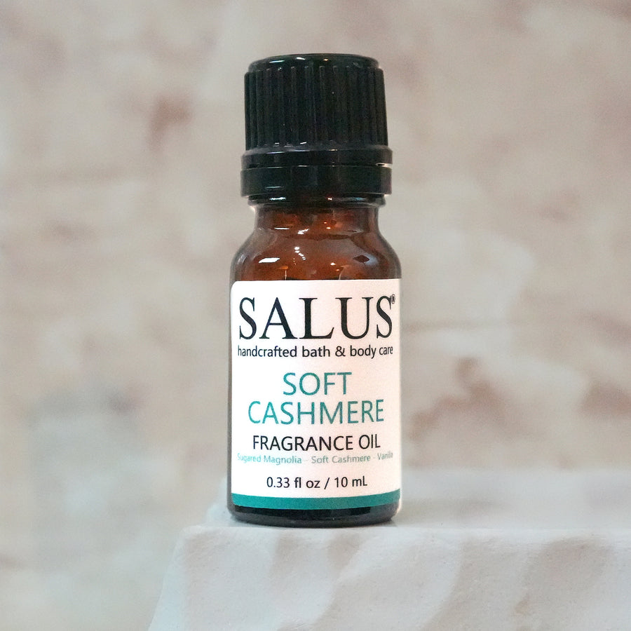 SALUS Soft Cashmere fragrance oil, 10 mL amber bottle on a white stone pedestal.