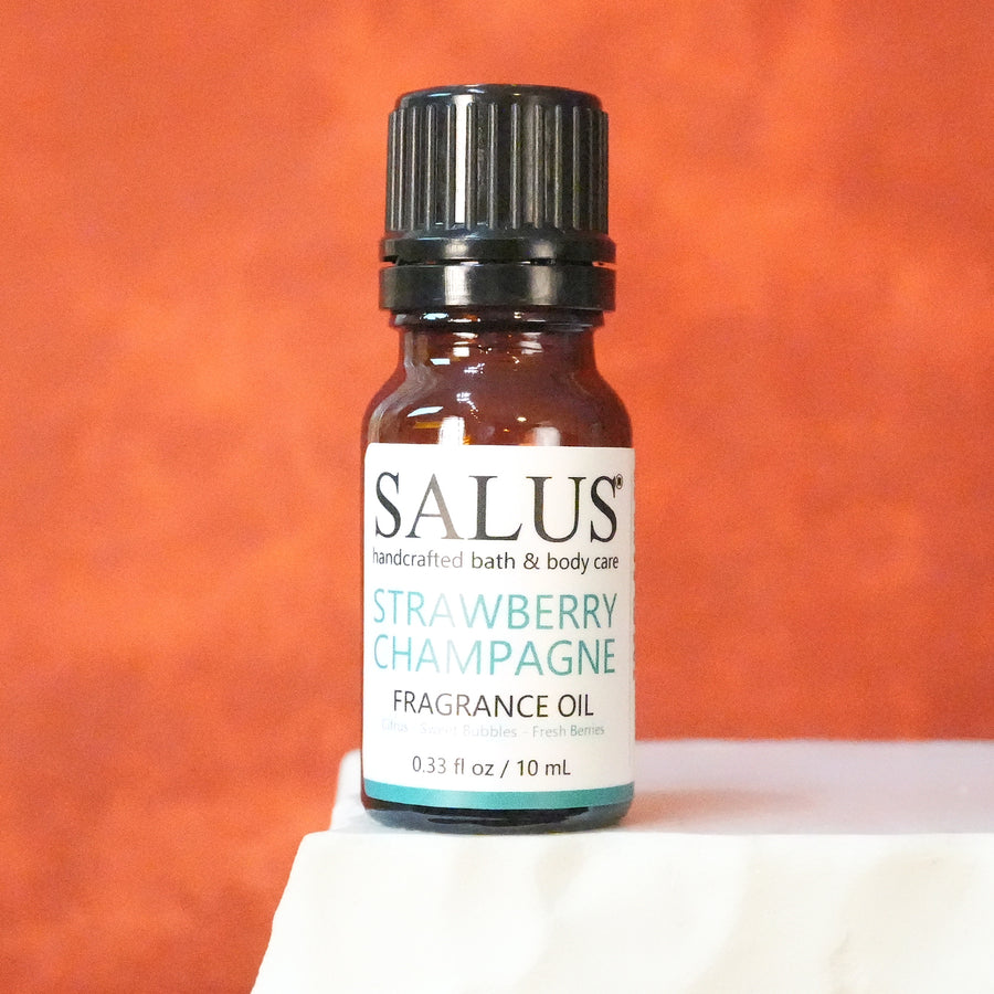 SALUS Strawberry Champagne fragrance oil, 10 mL amber bottle on a white stone pedestal.